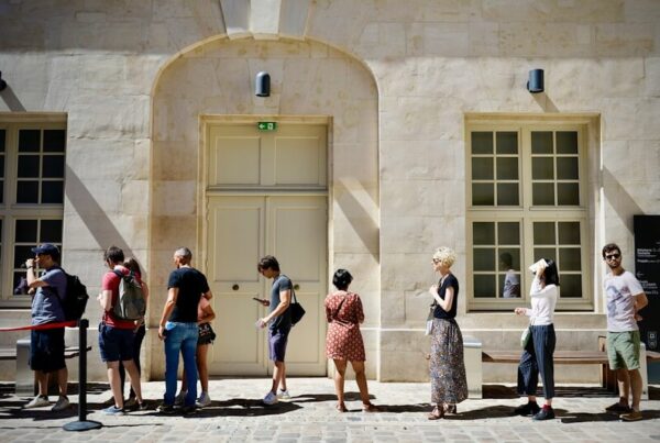 A queue of people standing outside a building, waiting in line