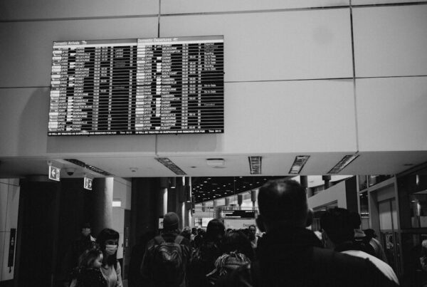 An airport departure board listing cancelled flights above a crowd of travellers, representing the external data source that settles a prediction market