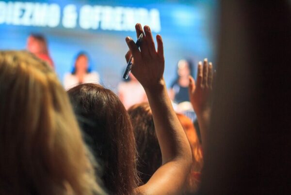 An audience at a conference raising their hands to vote