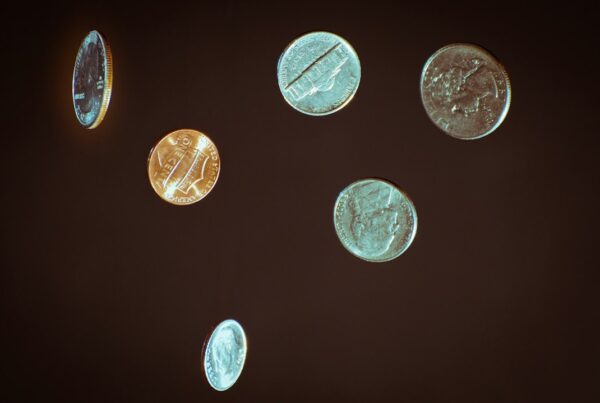 Six coins suspended in mid-air against a dark background, outcome undetermined