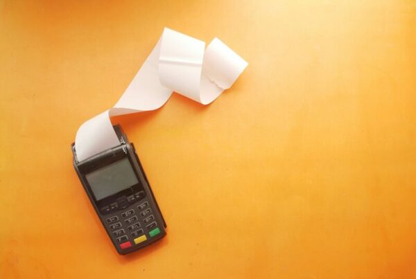 A card payment terminal with a blank paper receipt curling out of it