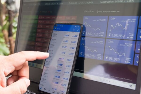 Hand pointing at a smartphone displaying live currency quotes