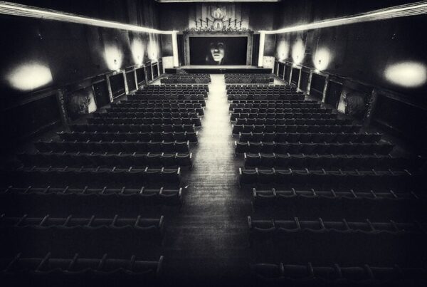 An empty vintage cinema auditorium with rows of seats facing a blank screen
