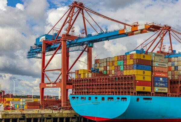 A gantry crane transferring shipping containers onto a container ship at a port