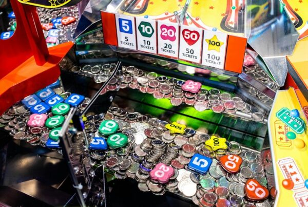 Close-up of an arcade coin pusher filled with tokens beneath a posted ticket-value chart