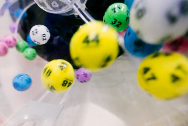 Colourful numbered lottery balls tumbling inside a clear plastic mixing machine
