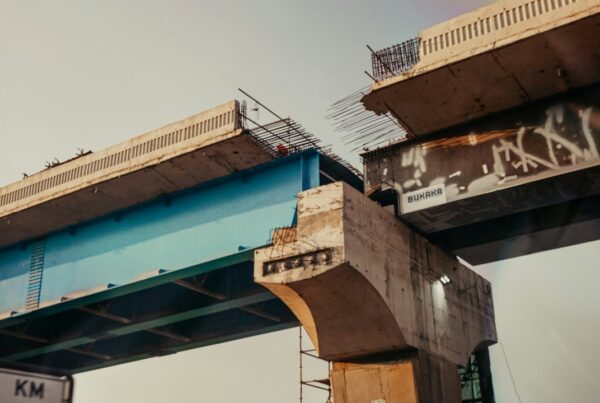 Two unfinished concrete bridge decks reaching towards each other with exposed rebar and an open gap between them