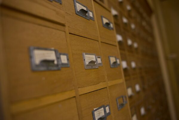 A wall of wooden card catalogue drawers, most label slots blank or unreadable, receding out of focus
