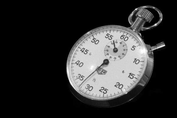A mechanical stopwatch on a black background, sweep hand mid-count