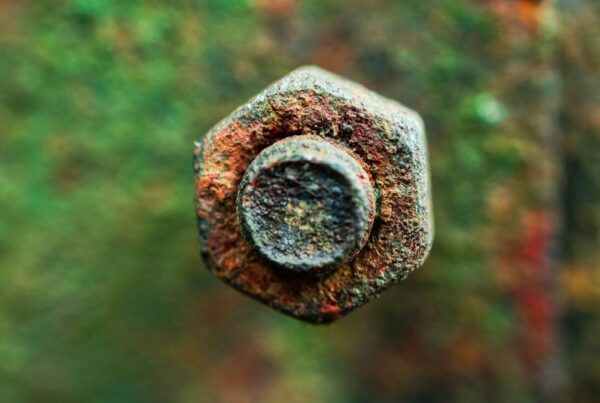 Close-up of a corroded hexagonal bolt head, still intact but seized in place